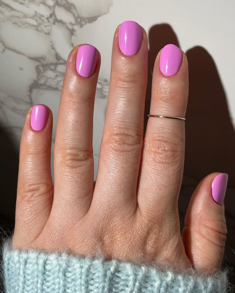 A woman's hand and finger nails wearing orly pink nail polish in taffy to be here, summer 2023 nail trends