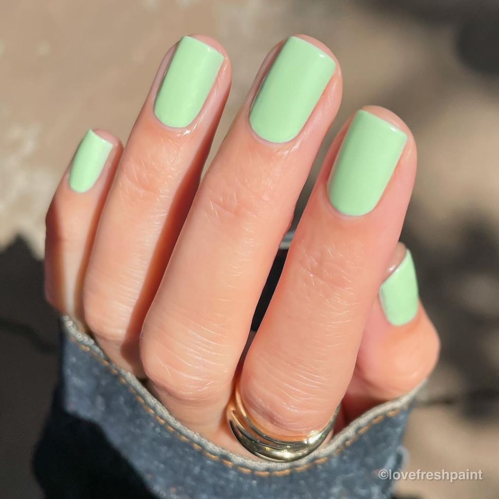 A woman's hand and finger nails wearing Ella+Mila green nail polish, Earth's Finest, summer 2023 nail trends
