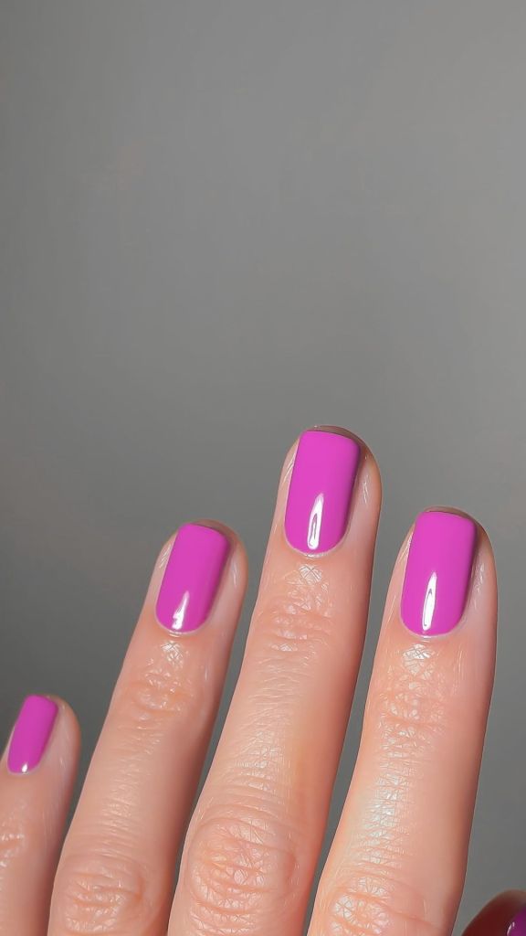 A woman's hand and finger nails wearing essie pink nail polish fuel your desire, summer 2023 nail trends