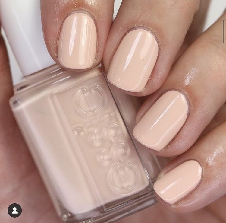 A woman's hand and finger nails wearing essie nude peach nail polish in angel food