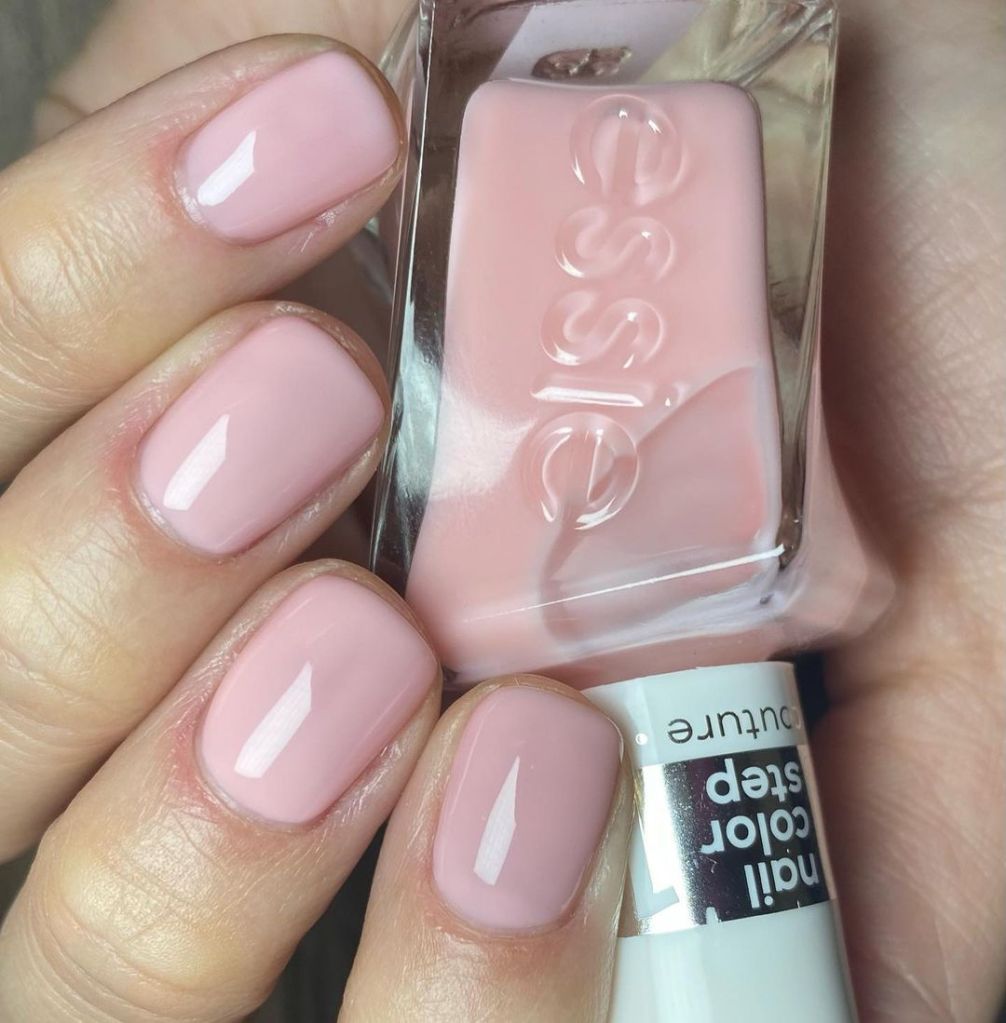 A woman's hand and finger nails wearing essie light pink nail polish in slip dress
