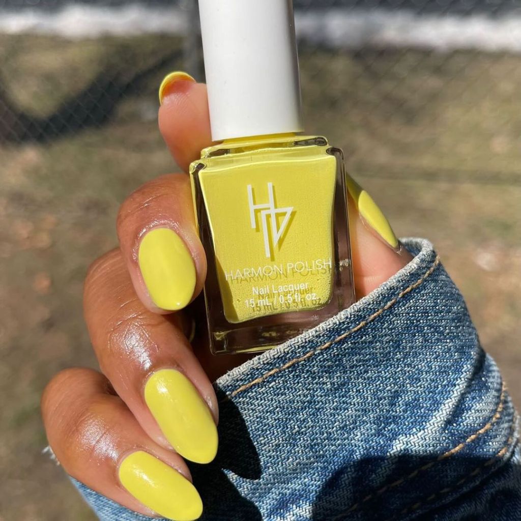 A black woman's hand and finger nails wearing Harmon Polish yellow nail polish, Self-Love