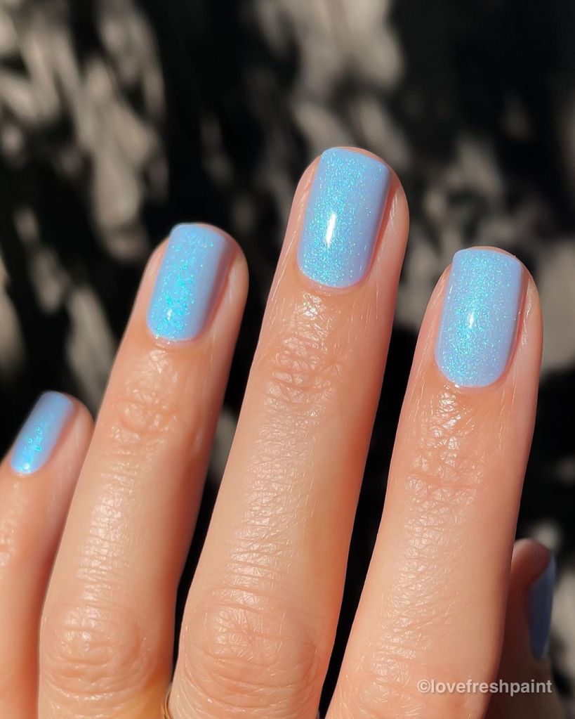 A woman's hand and finger nails wearing Mooncat light blue nail polish, Sabertooth, summer 2023 nail trends