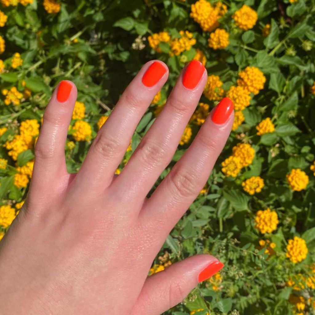 A woman's hand and finger nails wearing cirque red nail polish, Pyro, summer 2023 trendy nails