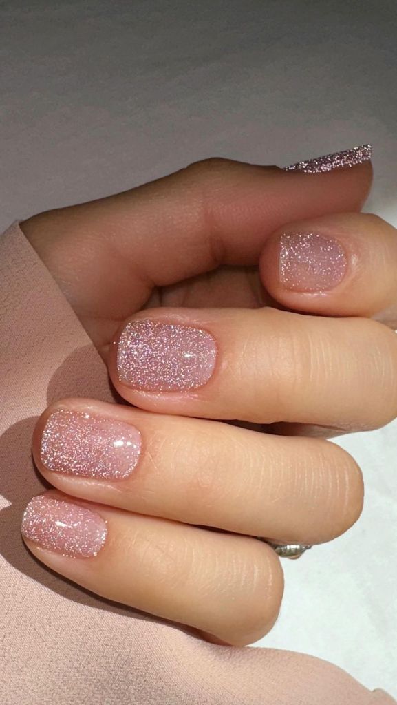 A woman's hand and finger nails wearing sparkly champagne, metallic nail polish from Brill Bird and CND World Shellac