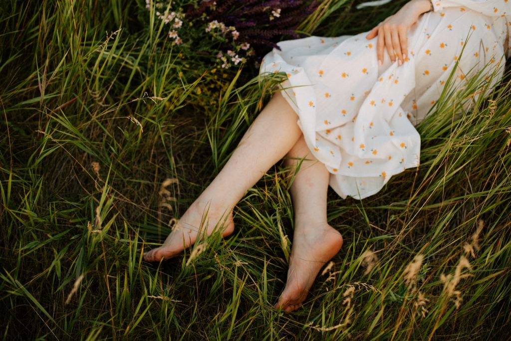 Grounding or Earthing : woman laying barefoot in field