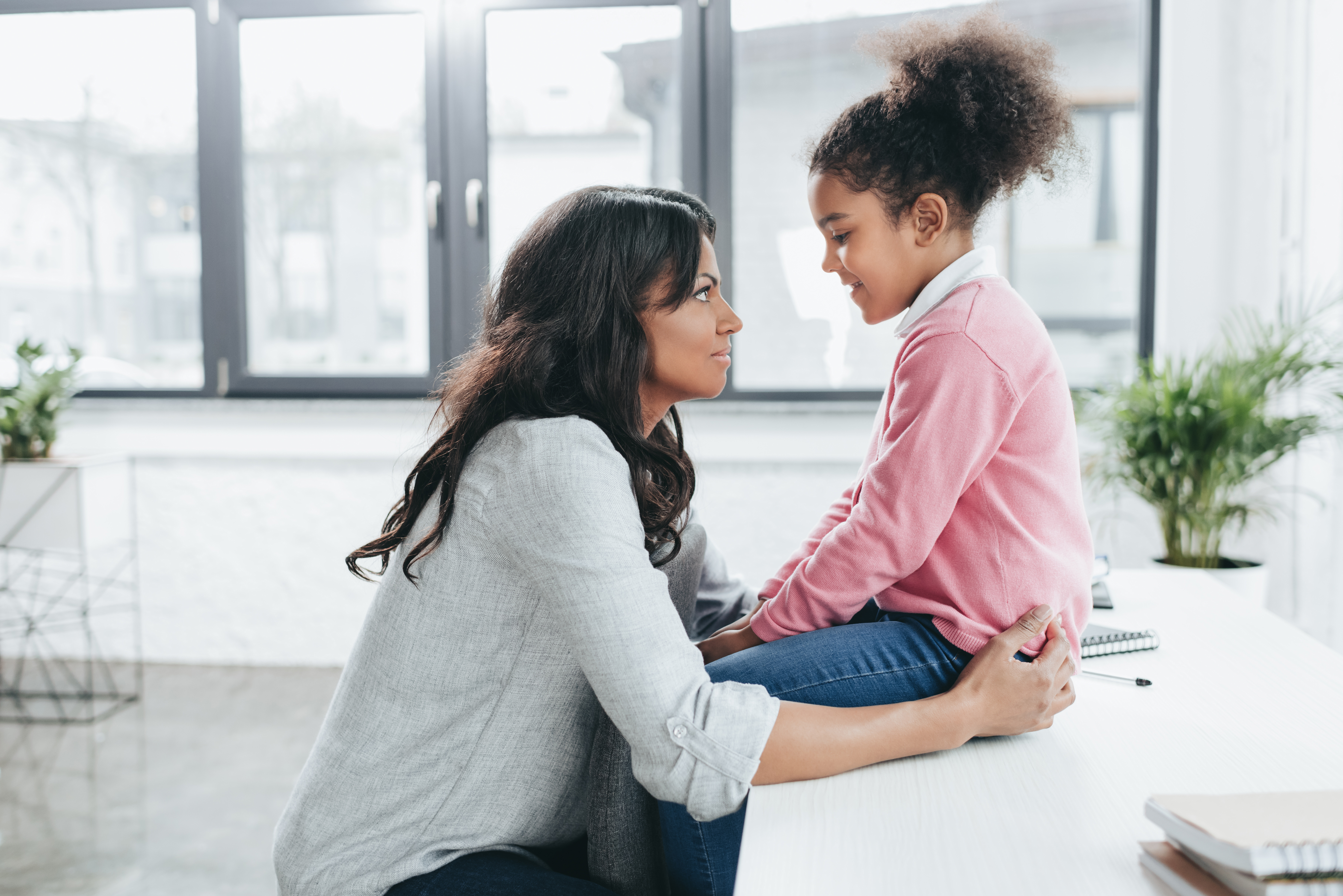 active listening: side view of african american mother talking with her daughter indoors